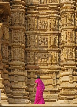 Tourist looking at erotic carvings on the Kandariya Mahadeva Temple at Khajuraho, India. 11th Century AD.