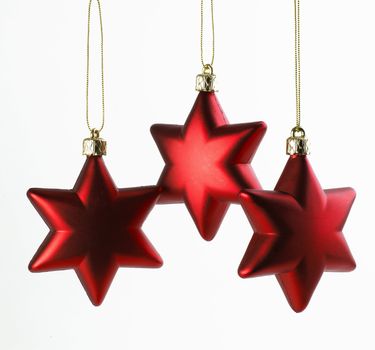 Three red Christmas Stars hanging on white background