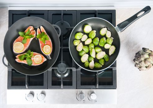 Red fish with mint and lemon prepared in a black skillet in the kitchen