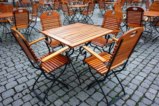 Picture of some wooden seats and tables outside..