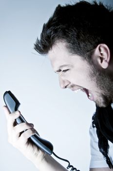 Angry young man shouting on the wired telephone