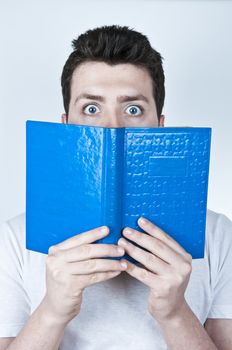 Isolated image of a young man afraid reading a book with blue hard cover