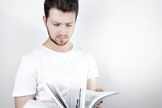 Isolated image of a young blonde man standing and reading a technical book