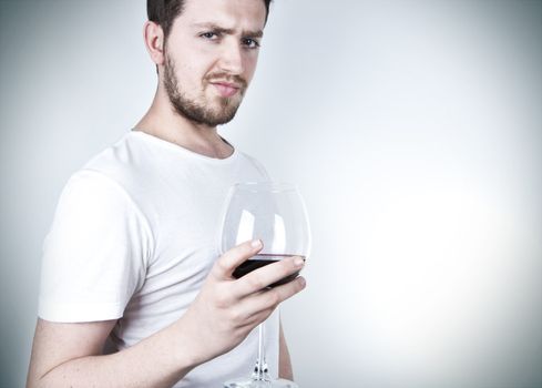 A young man posing with a glass of red wine