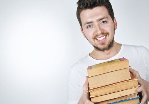 Isolated image of a young and happy man carrying a stack of old books