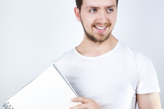 Isolated image of a young blonde man holding a notebook and smiling happily