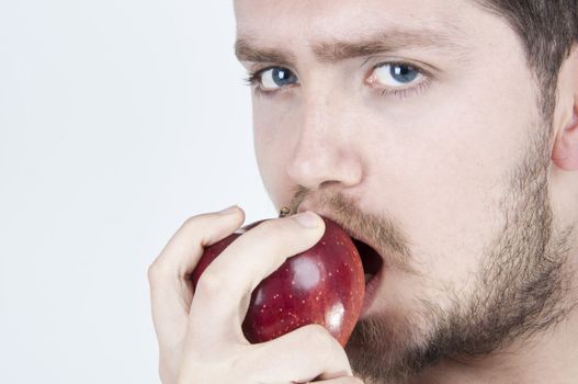 Isolated image of a young handsome man eating a red apple