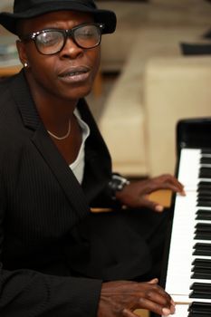 Black musician plays the piano and sings - shot by the side