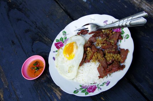 Fried Beff with Garlic Pepper on Rice and fried egg on wood table