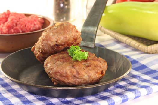 fried meatballs in a pan with fresh parsley