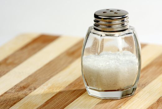 Glass salt-cellar on striped wooden plate