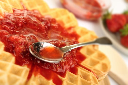 Fresh coocked pancakes topped with strawberries jam and  little spoon above