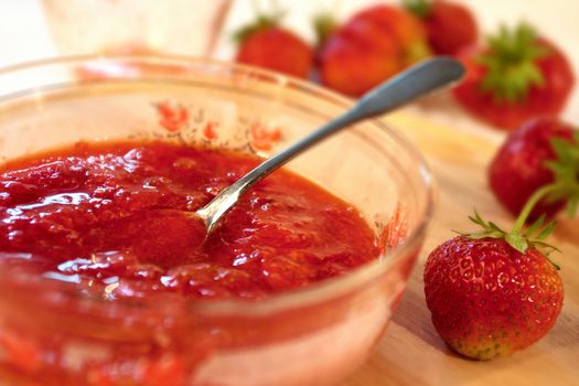 Strawberries jam in glass plate with spoon 