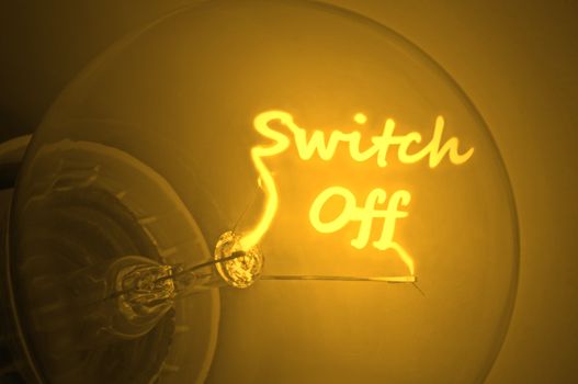 Close up of an illuminated yellow light bulb filament spelling the words switch off