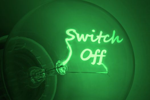 Close up on an illuminated green light bulb filament spelling the words switch off