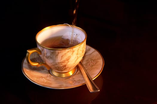 Boiling hot water being poured into a cup on a saucer with a tea bag