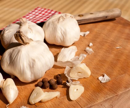 Garlic, kitchen knife and allspice on chopping board