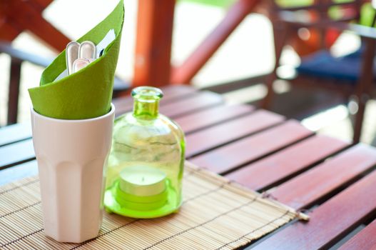 Cutlery and Glass Candleholder on Wooden Table in Garden Restaurant