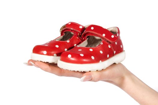 Woman hand holding baby red shoes over white