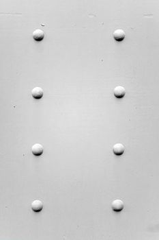 A painted metal background texture with four rusted bolts or rivets in black and white.