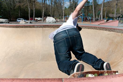 Action shot of a young skateboarder skating sideways against the wall of the bowl at a skate park.