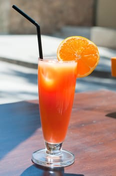 Shot of orange coctail with black straw