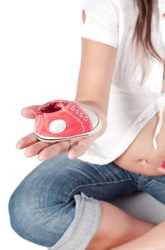 Beautiful pregnant woman with baby shoe on her palm