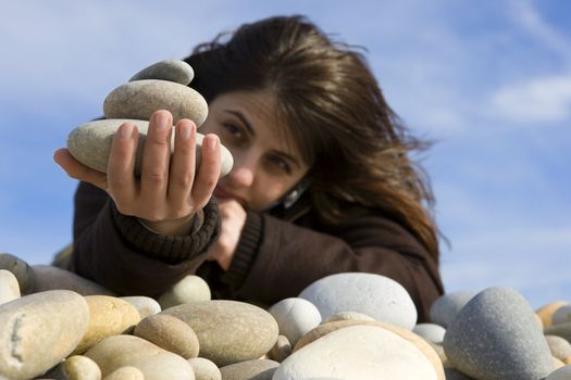 casual woman holding spa stones in the beach