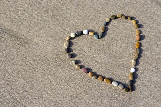 Heart made with small stone in the wet sand