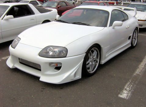 White sports car - customized with a body kit and rims.