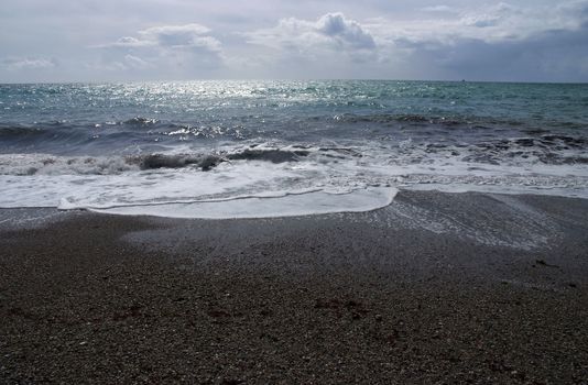 The coastline light with moonlight with the sea coming in over a shingle beach