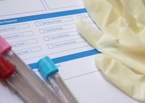 Preparation for a blood test with tubes, protective gloves and a request form.