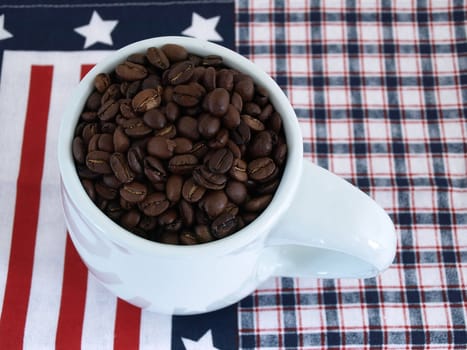 A blue coffee cup full of rich fresh beans over a red white and blue background.