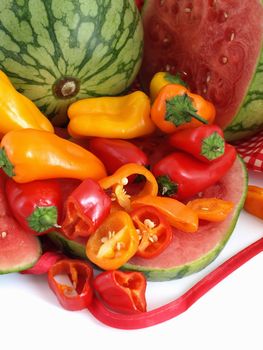 A vibrant summer crop of fresh juicy watermelon and colorful bell peppers, studio isolated over a white background.