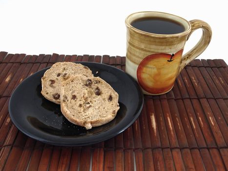 A cinnamon raisin muffin and a hot cup of coffee on a bamboo mat. Isolated over white.