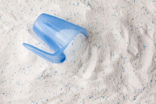 Laundry detergent powder for washing machine and plastic scoop for dosage.