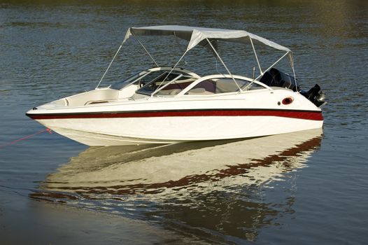 A moored boat reflects on the surface of a river.