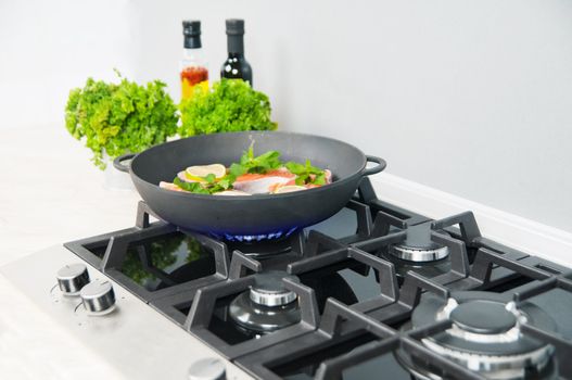 Red fish with mint and lemon prepared in a black skillet in the kitchen