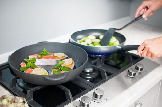 Red fish with mint and lemon prepared in a black skillet in the kitchen