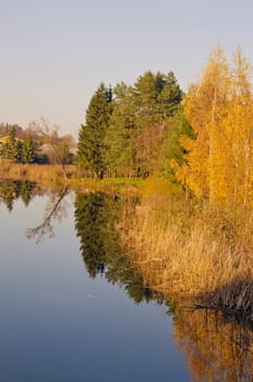 Lake with reflection of trees with colored leaves in autumn.