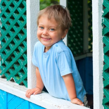 Cute 2 years old boy sitting in the summer house in park