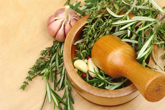 Mortar with garlic, peppercorns, rosemary and thyme on wooden board (Selective Focus)  