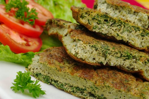 Omelette with herbs on white plate with parsley, lettuce and tomato slices (Selective Focus)