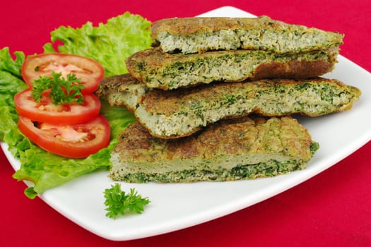 Omelette with herbs with parsley, lettuce and tomato slices, on white plate and red tablecloth (Selective Focus)