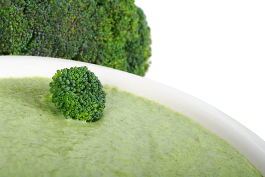 Broccoli cream soup on white plate with broccoli in the background (Selective Focus, Isolated) 