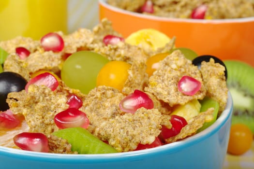 Fruits and Cereals in colorful bowls with orange juice in the background