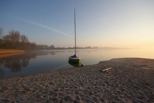 Small sailing boat in morning light and mist 