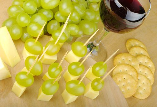 Cheese, grapes and Wine as fingerfood on a wooden board (Selective Focus, tilted)