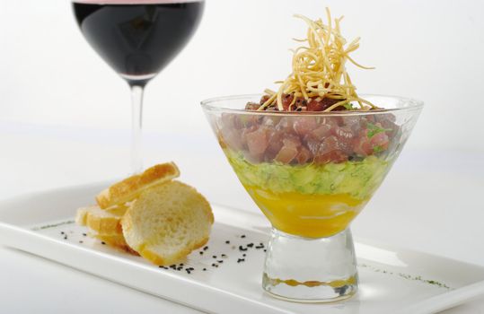 Appetizer: Raw Tuna, Avocado and Mango in Glass, with Baguette and a Glass of Red Wine (Selective Focus)