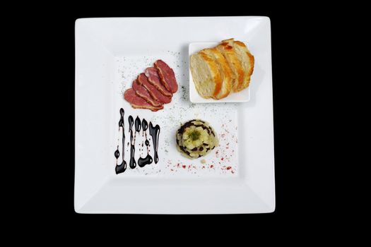 Appetizer: Duck Meat, Blood Sausage, Apples and Baguette on White Plate and Black Background Photographed from Above (Isolated) 